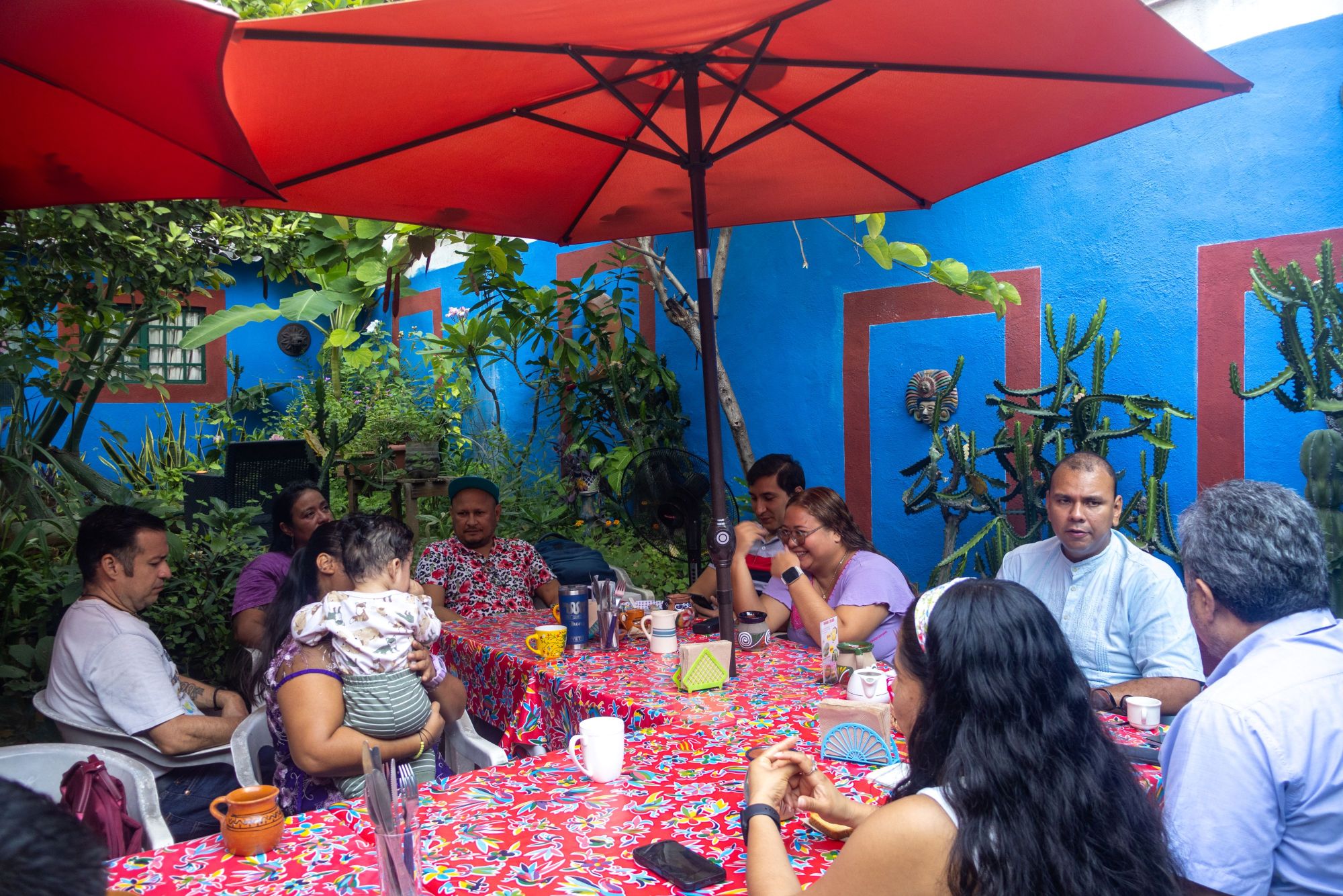 A group of people from the network sitting around a table with a red parasol above